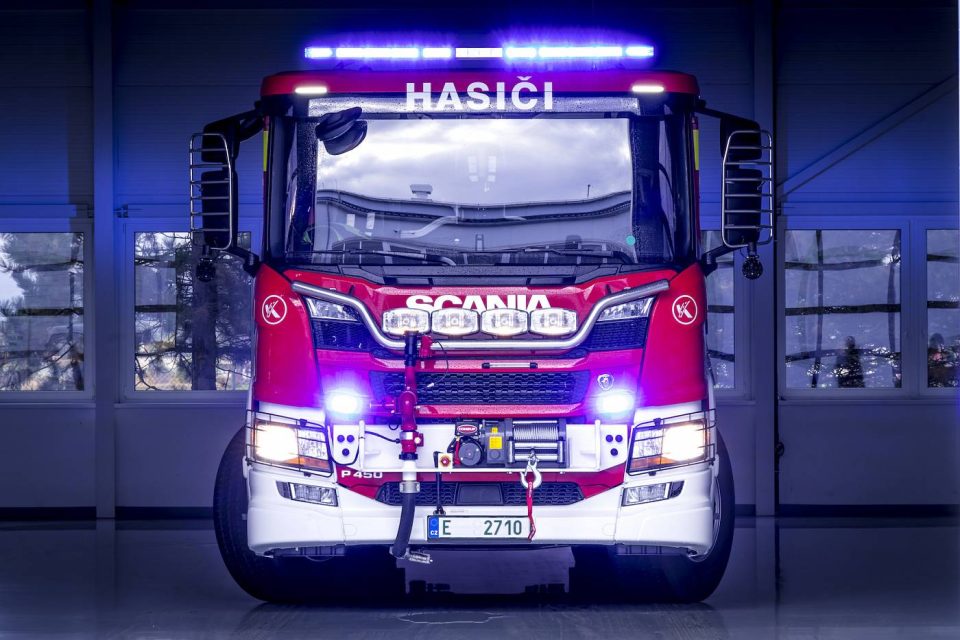 Červený hasičský vůz Scania s rozsvícenými majáky v garáži – požární dohled APS-FIRE